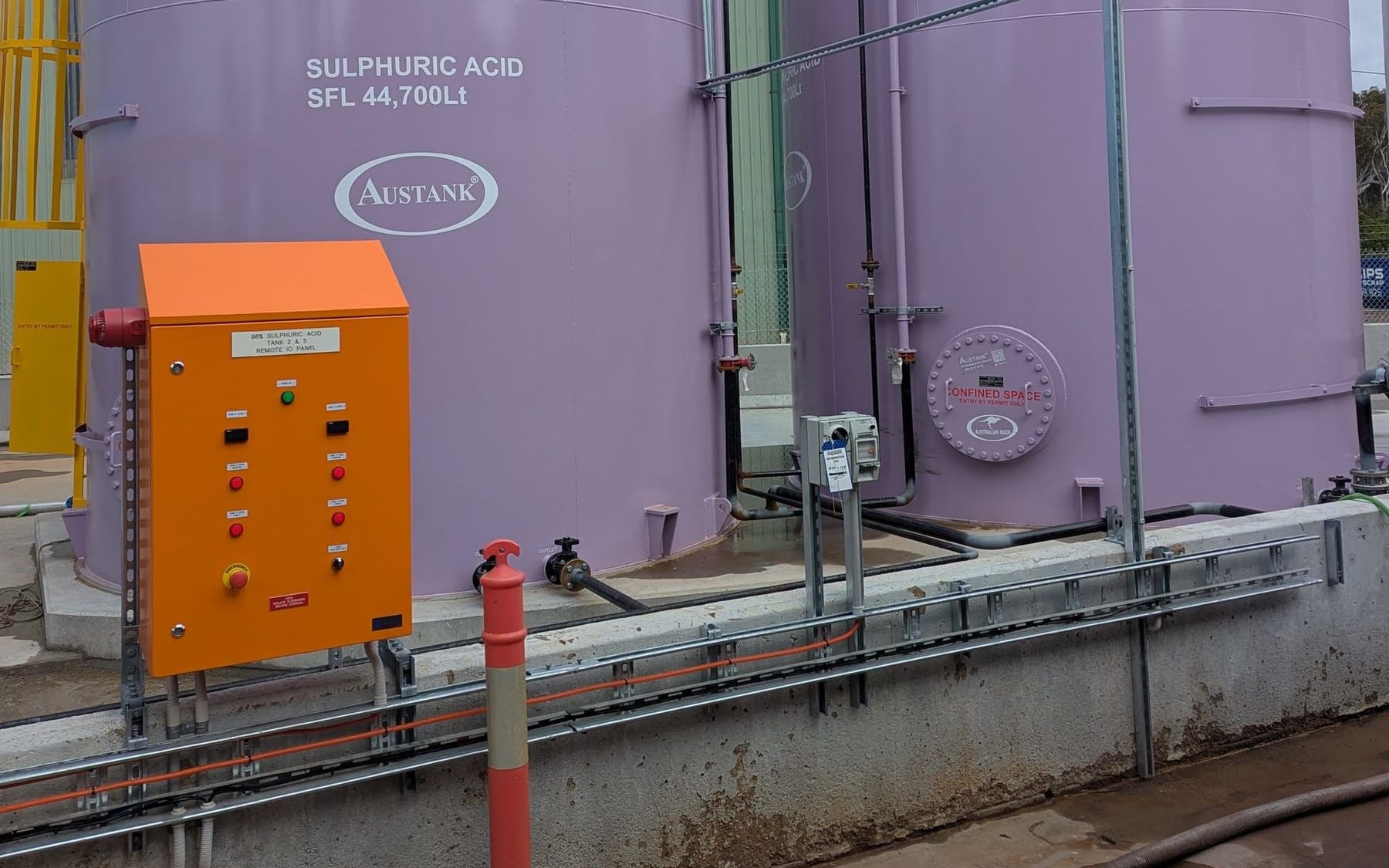 Remote IO panel beside two sulphuric acid storage tanks at a chemical plant