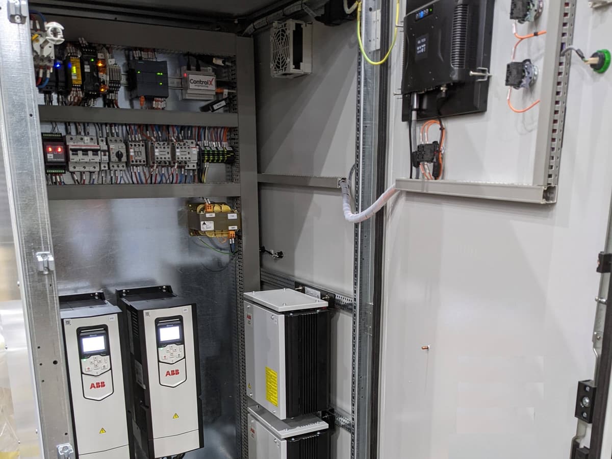 Floor-standing control panel with PLC, two variable-speed drives and an operator screen on the door