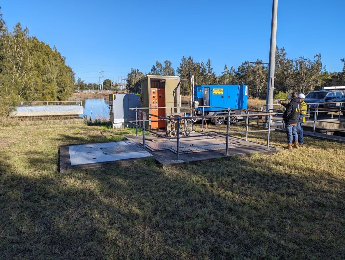 Pump station platform with control cabinet and generator beside a dam